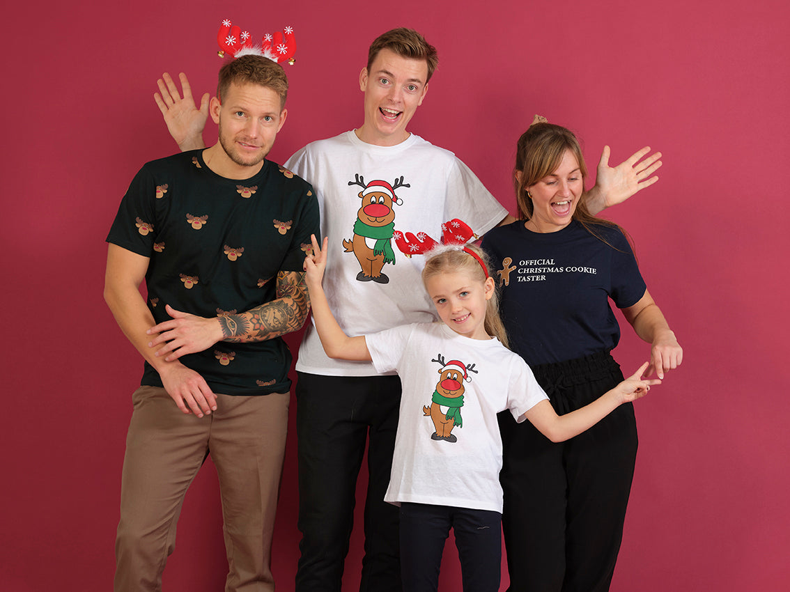 To mænd, en kvinde og et barn er alle iført jule T-shirts med juletema.